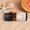 Bottle of Beach Vibes Essential Oil Blend on sandy beach with starfish, sea shells, and half of an orange, evoking summer relaxation.